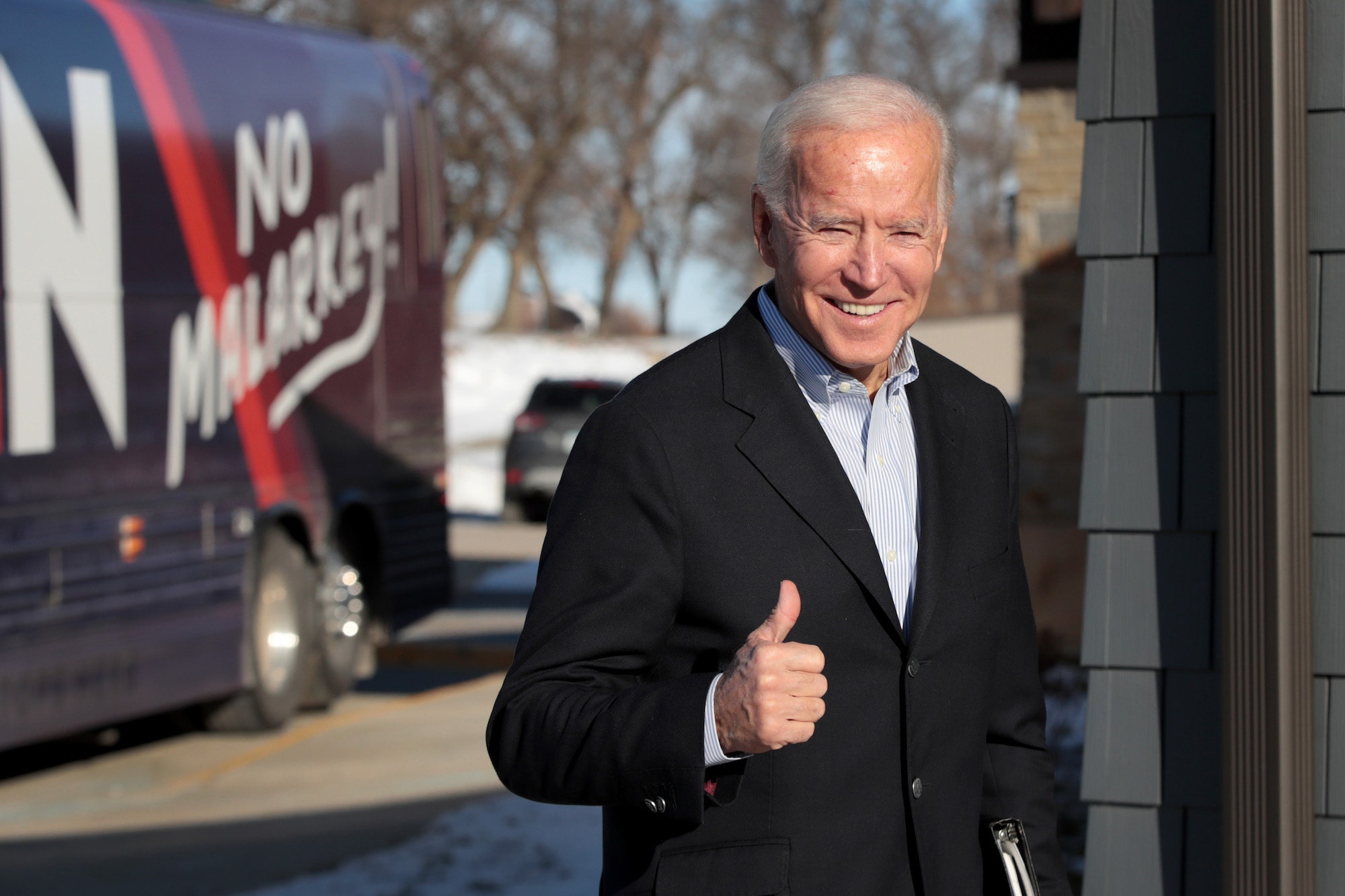Image may contain Clothing Apparel Human Person Finger Suit Coat Overcoat Thumbs Up Vehicle and Transportation