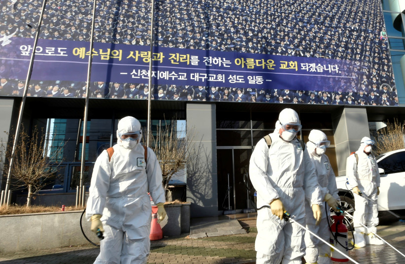 Workers from a disinfection service company sanitize a street in front of a branch of the Shincheonji Church of Jesus the Temple of the Tabernacle of the Testimony where a woman known as Patient 31 attended a service in Daegu, South Korea, February 19, 2020 (photo credit: YONHAP VIA REUTERS)